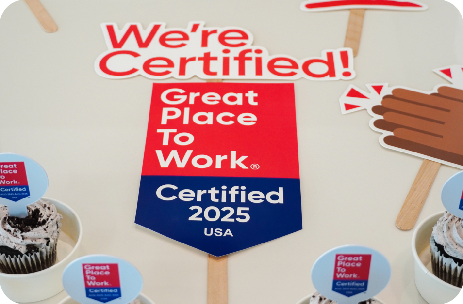 Great Place to Work Certified 2025 USA display surrounded by celebration props and branded cupcakes during a workplace event.