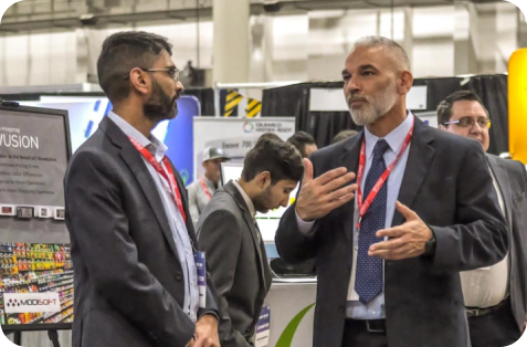 Attendees engage in conversation at a trade show booth, highlighting Modisoft's presence at an industry networking and technology event.