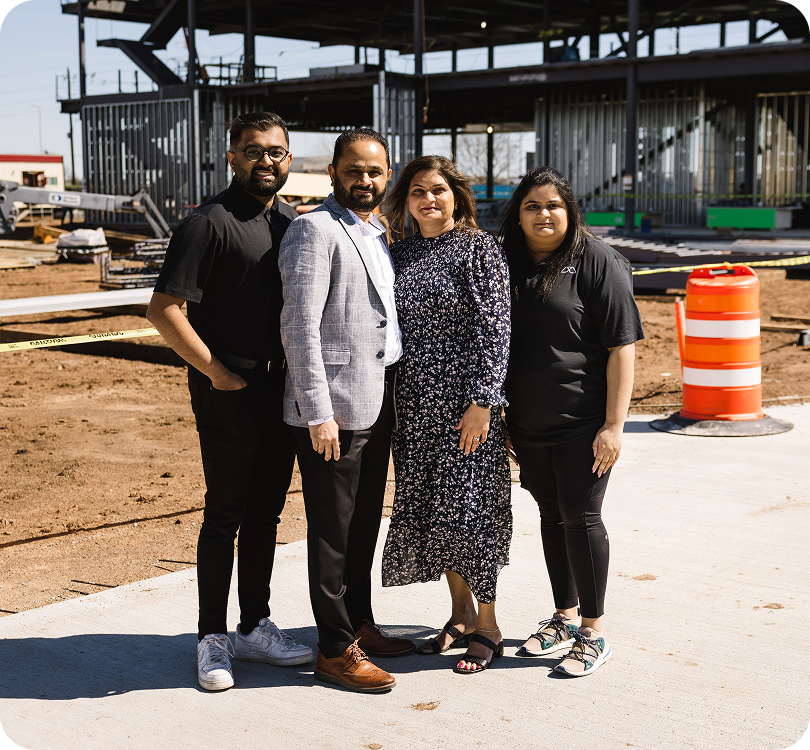 For modisoft members standing at an active construction site with steel building framework in the background.