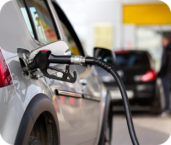 Fuel pump dispensing fuel into a vehicle at a gas station forecourt.