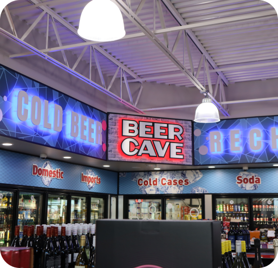 Convenience store interior featuring beverage coolers, product displays, and illuminated Beer Cave signage.